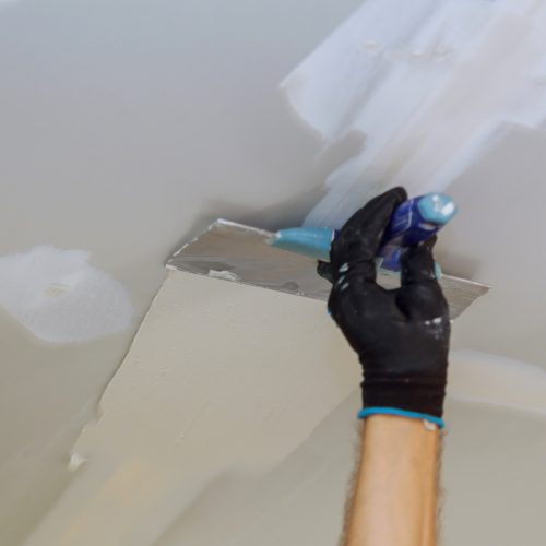 Closeup of a man aligning a wall with spatula and plastering gypsum cardboard wall