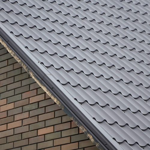 Modern brown roof made of painted metal. Corrugated metal roof and metal roofing industry concept